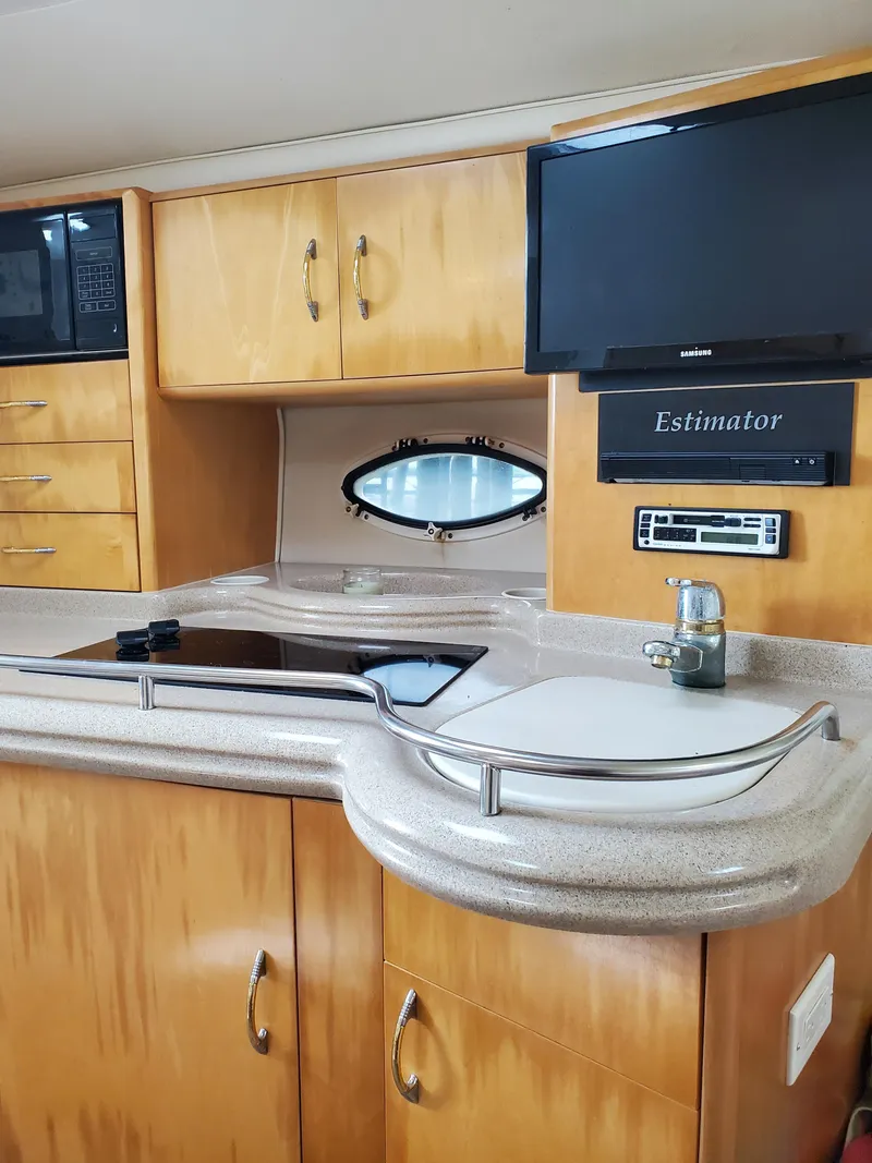 Slide: The Image of 2000 Larson 330 CABRIO yacht interior kitchen with stove, sink, and cabinets. - 22