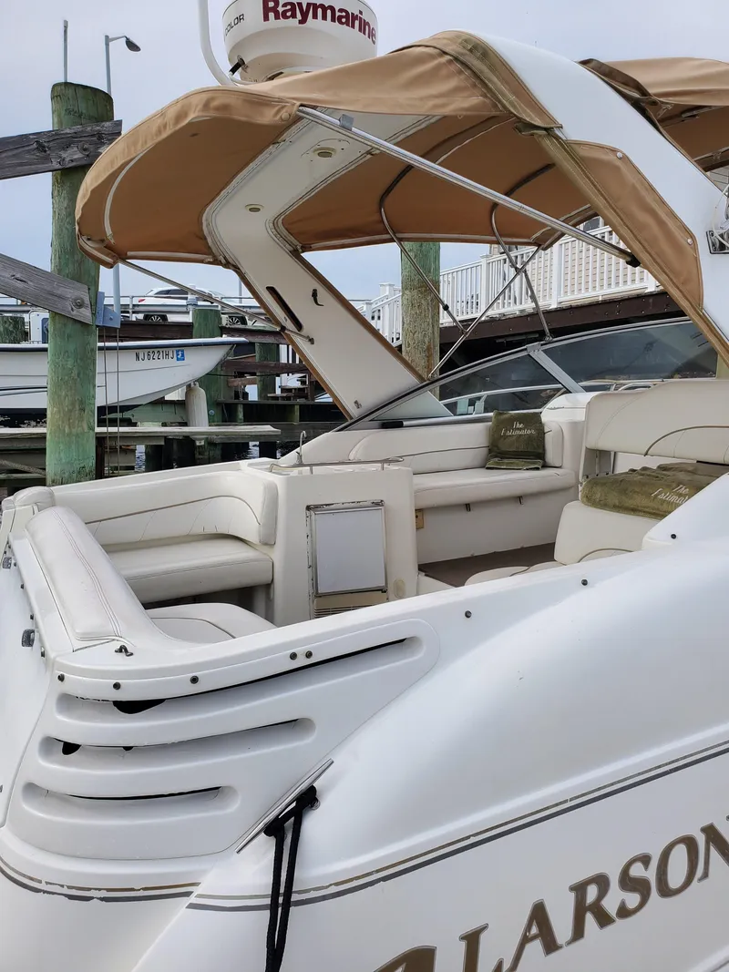 Slide: The Image of 2000 Larson 330 Cabrio boat with tan canopy and white seating at a dock. - 26