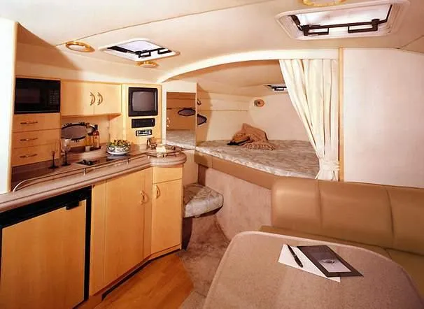 Slide: The Image of Interior of a 2000 Larson 330 Cabrio boat, featuring a cozy cabin with kitchenette and bed. - 28