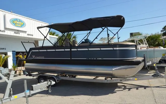Slide: The Image of 2025 Viaggio Lago X 22 U pontoon boat on trailer, parked outside dealership. - 11