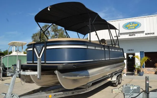 Slide: The Image of 2025 Viaggio Lago X 22 U pontoon boat on trailer, parked outside dealership. - 3