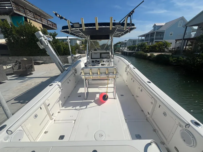 Slide: The Image of 2004 Century 2900 Center Console boat docked by a canal, featuring spacious deck and fishing equipment. - 14