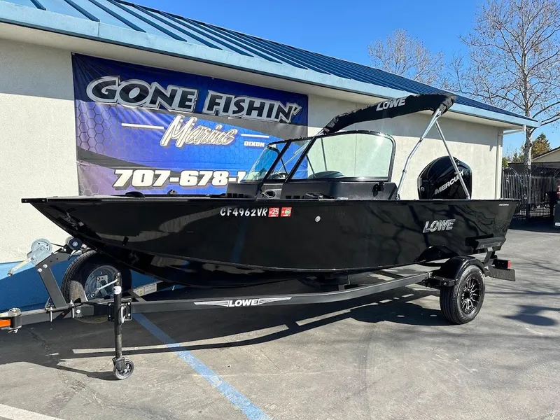 Slide: The Image of 2019 Lowe FM 165 Pro WT fishing boat on trailer, parked outside a dealership. - 2