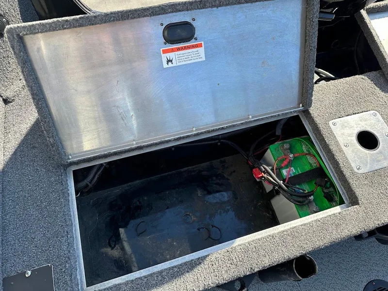 Slide: The Image of Open storage compartment in a 2019 Lowe FM 165 Pro WT boat, showing battery and wiring. - 32