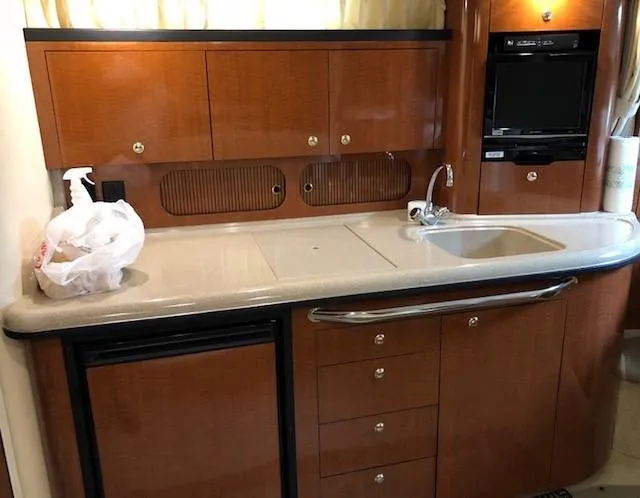 Slide: The Image of 2003 Sea Ray 340 Sundancer kitchen with wood cabinets, sink, and mini fridge. - 13