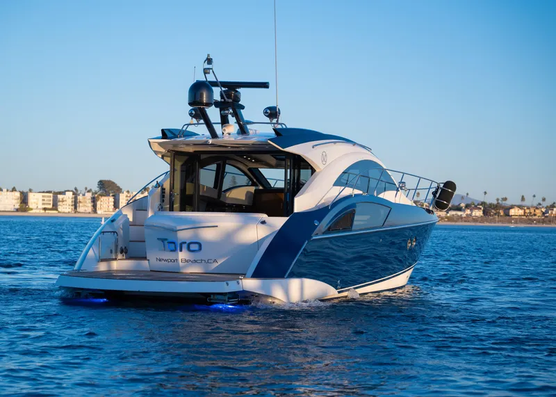 Slide: The Image of 2009 Marquis 420 Sport Coupe yacht cruising on calm waters near a coastal city. - 6