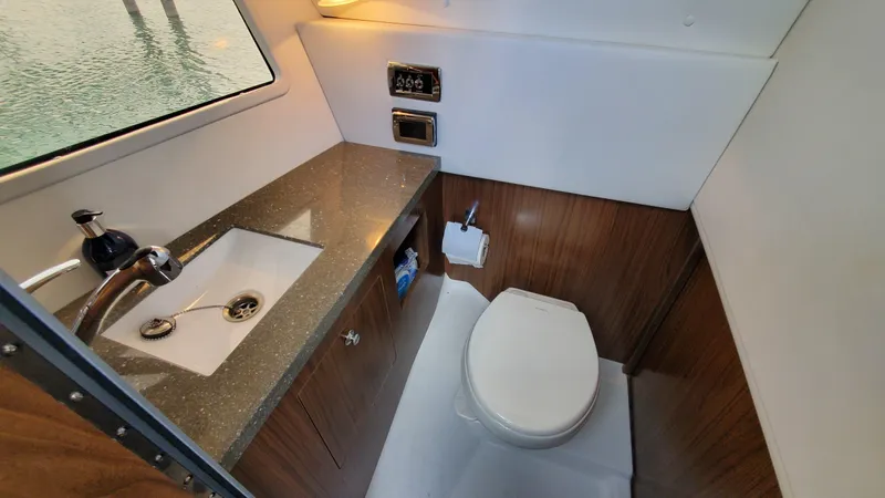 Slide: The Image of 2021 Four Winns H350 boat bathroom with sink, toilet, and wooden cabinetry. - 32