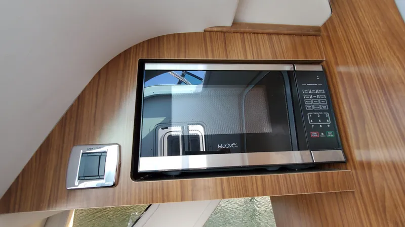 Slide: The Image of Microwave in 2021 Four Winns H350 boat interior, featuring sleek wood paneling. - 33
