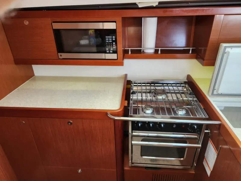 Slide: The Image of Beneteau Oceanis 50 yacht kitchen with stove, microwave, and wooden cabinetry, 2012 model. - 35