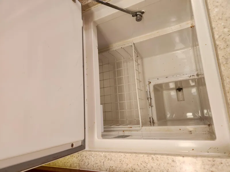 Slide: The Image of Open storage compartment on 2012 Beneteau Oceanis 50 yacht, featuring a white interior and wire basket. - 36