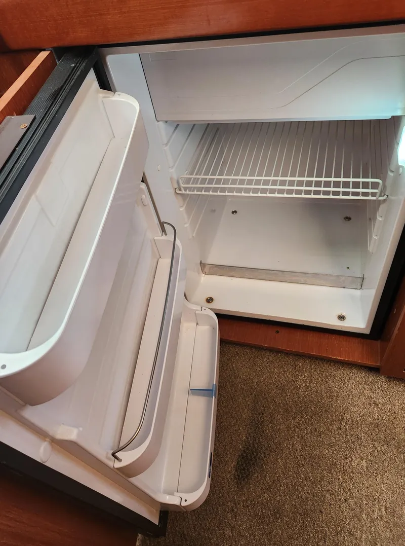 Slide: The Image of Open refrigerator inside 2012 Beneteau Oceanis 50 yacht, showing empty shelves and door compartments. - 37