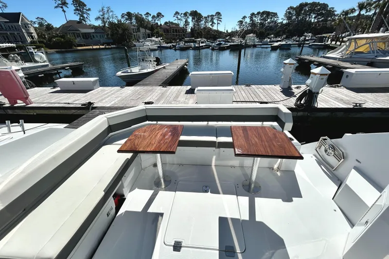 Slide: The Image of 2022 Cruisers Yachts 42 Cantius docked, featuring spacious outdoor seating and wooden tables. - 14