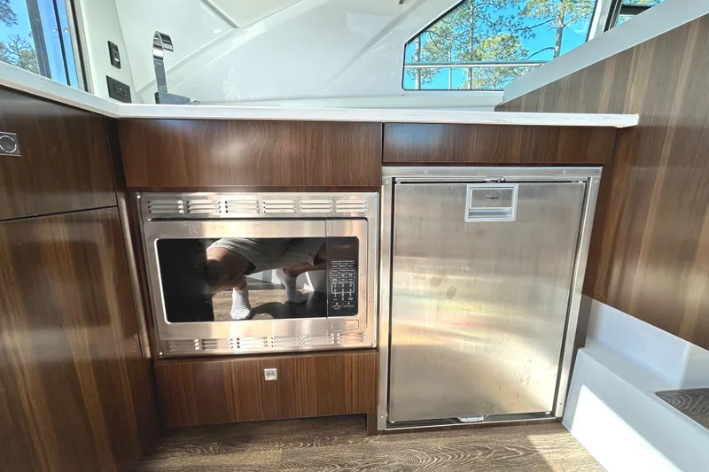 Slide: The Image of 2022 Cruisers Yachts 42 Cantius kitchen with microwave and stainless steel fridge. - 28