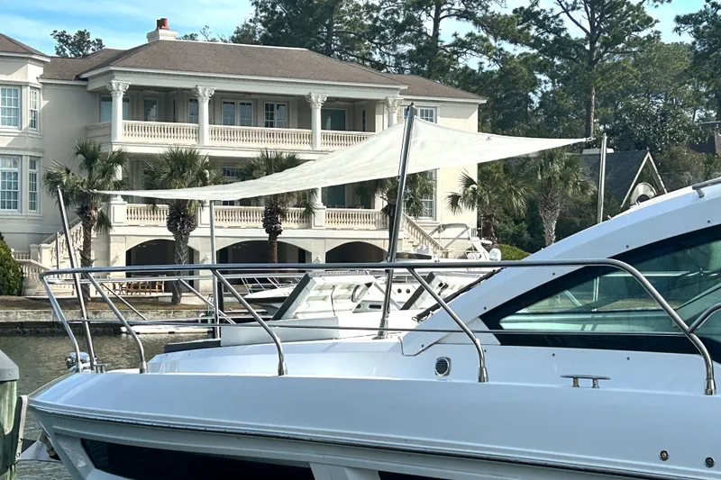 Slide: The Image of 2022 Cruisers Yachts 42 Cantius docked near a luxurious waterfront home. - 7