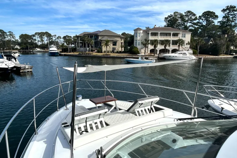 Slide: The Image of 2022 Cruisers Yachts 42 Cantius docked in a scenic marina with luxury homes. - 8