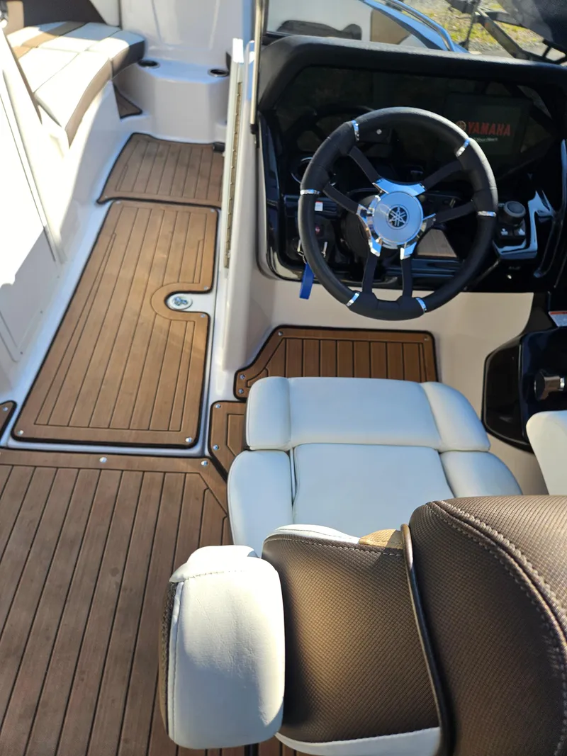 Slide: The Image of 2022 Yamaha Boats 212S interior with sleek steering and wood-style flooring. - 12