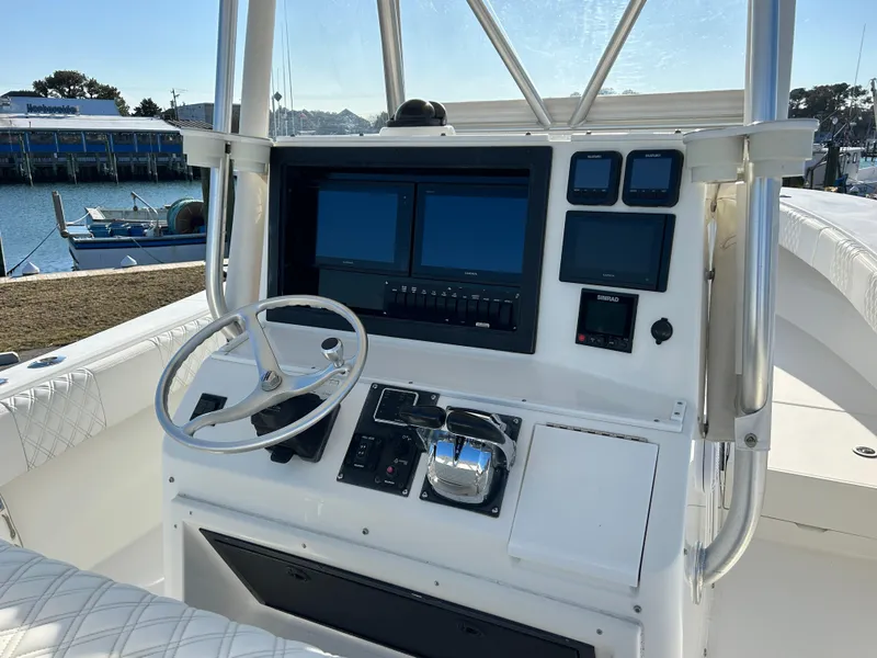 Slide: The Image of Control console of a 2000 Regulator 32 Classic boat with steering wheel and navigation screens. - 13