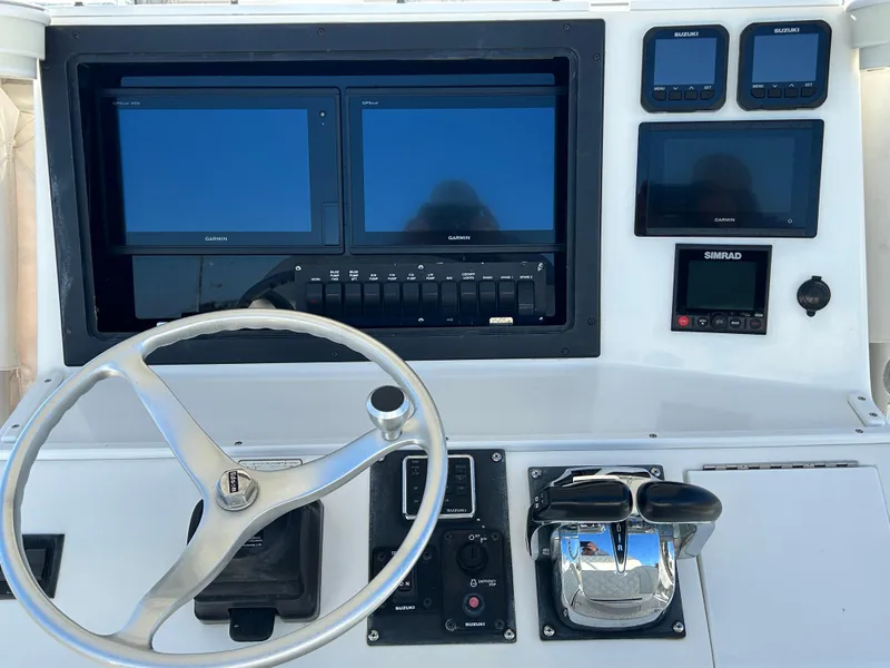 Slide: The Image of Control panel of a 2000 Regulator 32 Classic boat with navigation screens and steering wheel. - 14