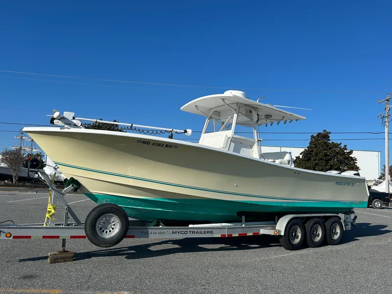 Slide: The Image of 2000 Regulator 32 Classic boat on a trailer, parked outdoors under a clear blue sky. - 2