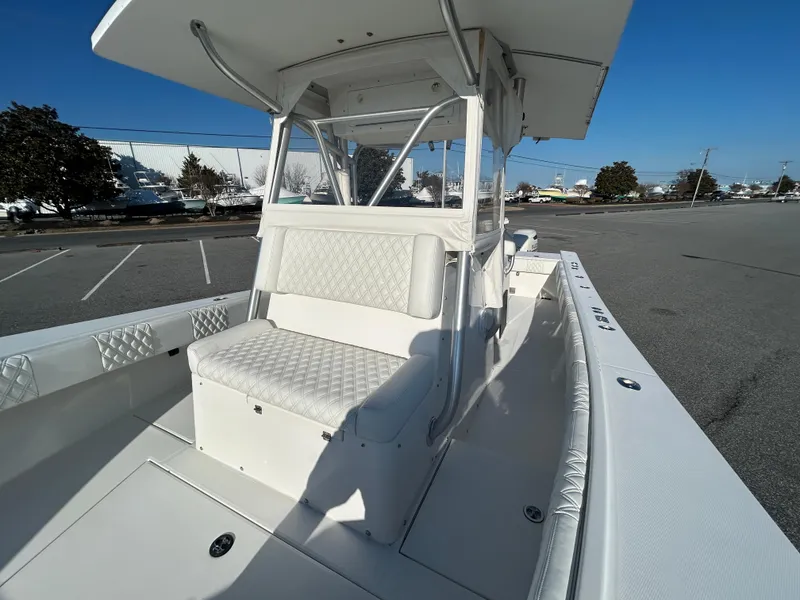 Slide: The Image of 2000 Regulator 32 Classic boat with white seating and canopy in a parking lot. - 27