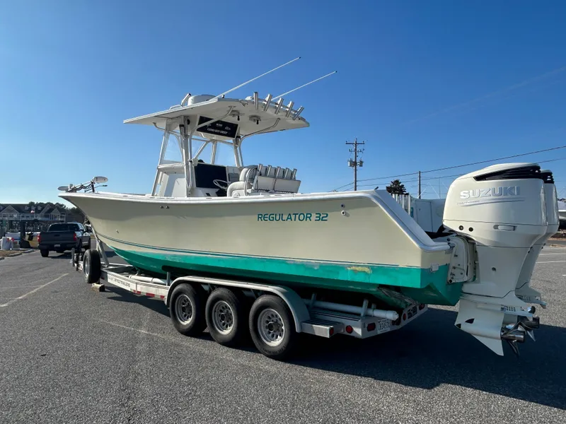 Slide: The Image of 2000 Regulator 32 Classic boat on trailer with Suzuki outboard motor, parked outdoors. - 3