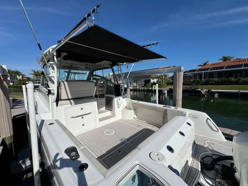 Slide: The Image of 2017 Boston Whaler 315 Conquest boat docked, featuring spacious deck and canopy. - 17