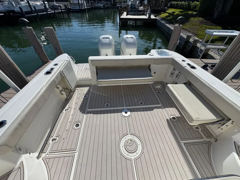 Slide: The Image of 2017 Boston Whaler 315 Conquest boat deck with seating, docked by the water. - 18