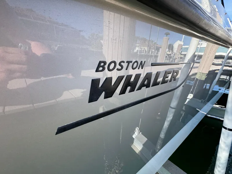 Slide: The Image of 2017 Boston Whaler 315 Conquest boat logo on hull, docked in marina. - 28