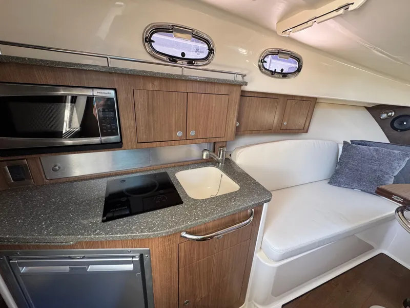 Slide: The Image of 2017 Boston Whaler 315 Conquest interior with kitchenette, sink, and seating area. - 8