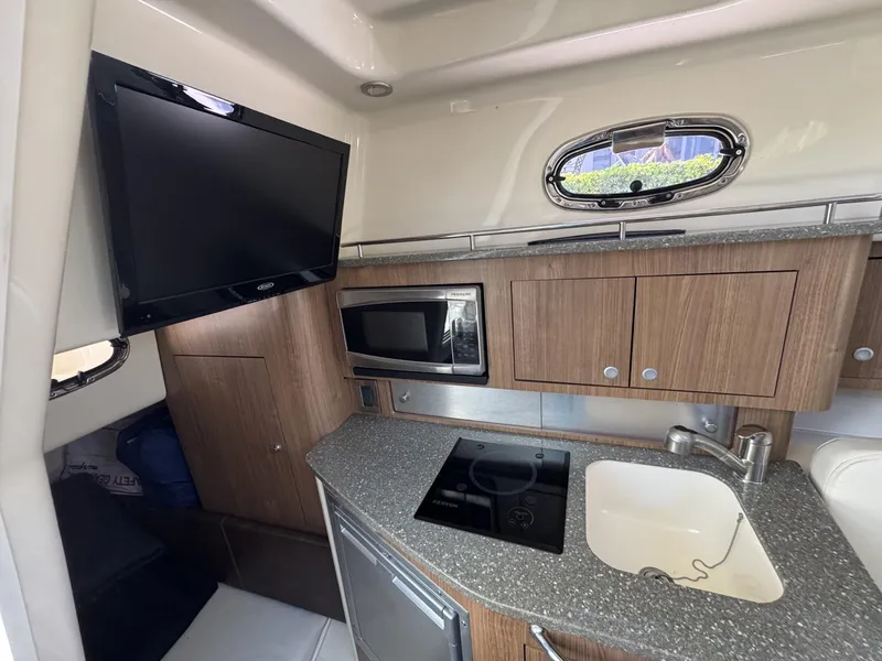 Slide: The Image of Interior of 2017 Boston Whaler 315 Conquest with kitchenette, TV, and modern amenities. - 9