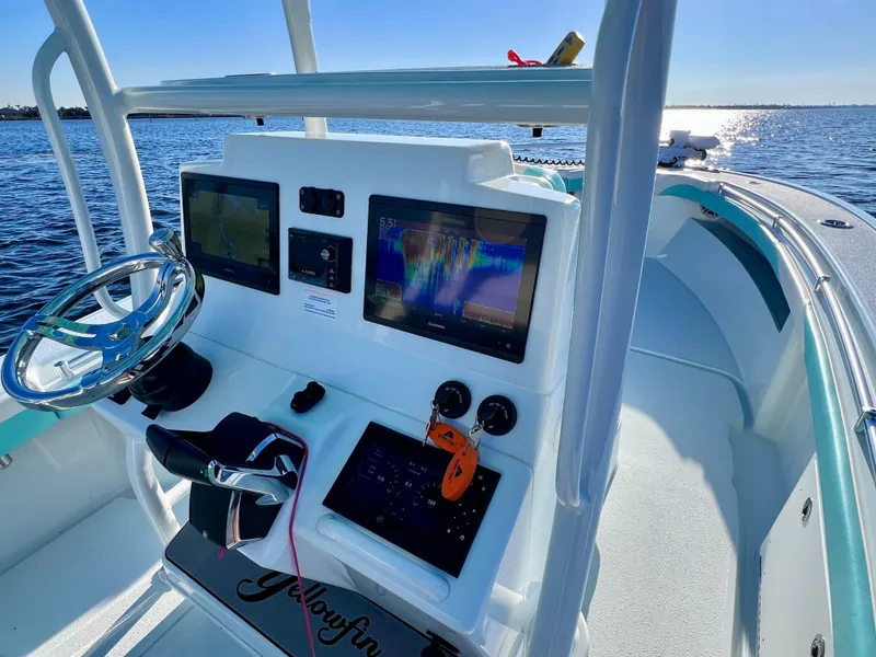 Slide: The Image of 2022 Yellowfin 26 Hybrid boat dashboard with advanced navigation systems on open water. - 24