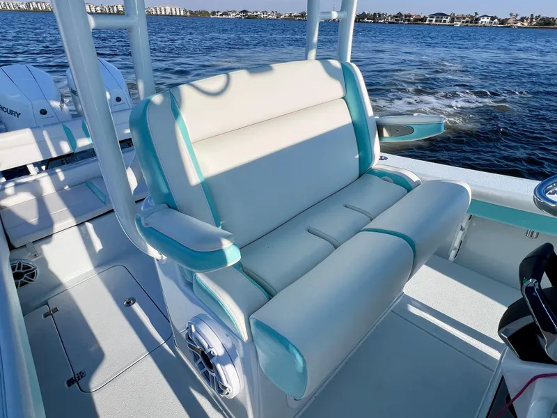 Slide: The Image of 2022 Yellowfin 26 Hybrid boat interior with cushioned seating, twin Mercury engines, and ocean backdrop. - 26