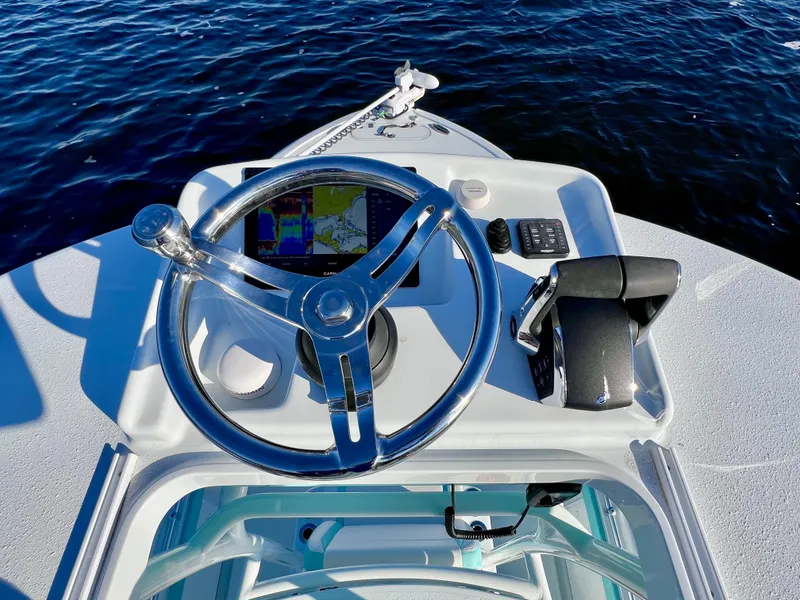 Slide: The Image of 2022 Yellowfin 26 Hybrid boat helm with navigation system and controls, on calm water. - 38