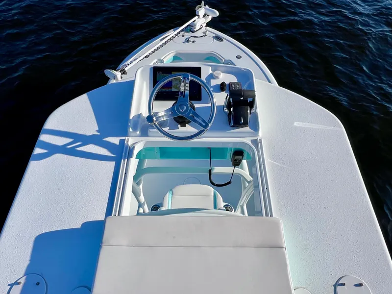 Slide: The Image of 2022 Yellowfin 26 Hybrid boat helm with steering wheel and controls, on calm water. - 44