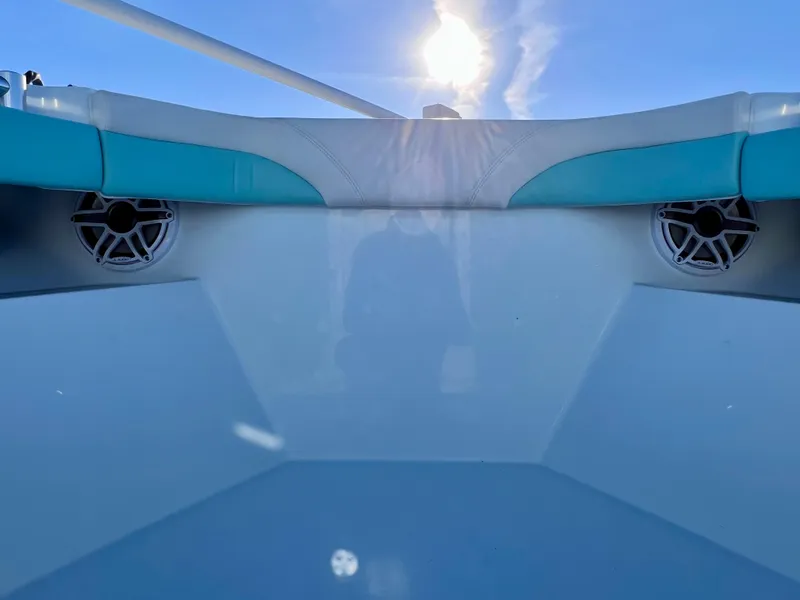 Slide: The Image of 2022 Yellowfin 26 Hybrid boat interior with teal accents and speakers, under clear blue sky. - 47