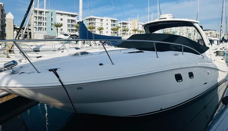 Slide: The Image of 2007 Sea Ray 310 Sundancer docked at marina, sleek white design, modern architecture in background. - 1