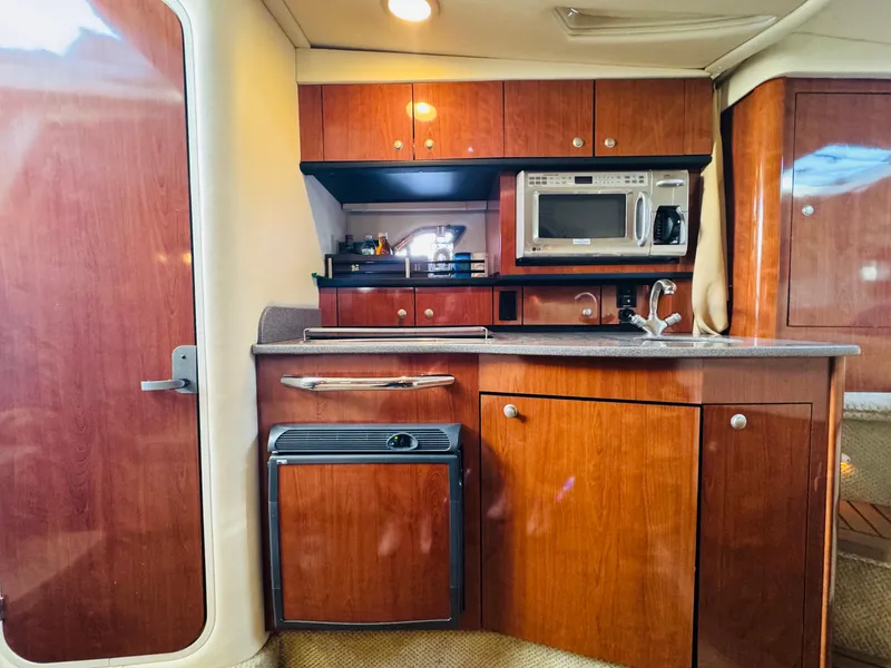 Slide: The Image of Interior of 2007 Sea Ray 310 Sundancer with wooden cabinetry and kitchenette. - 13