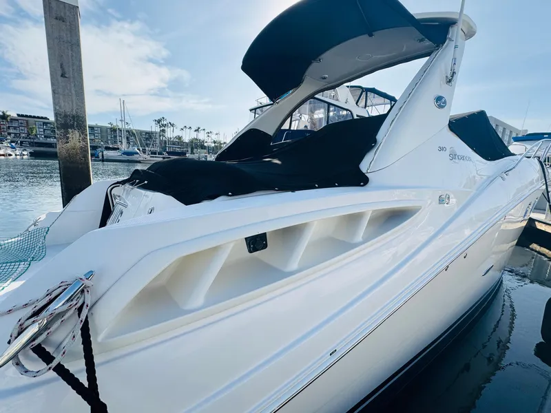 Slide: The Image of 2007 Sea Ray 310 Sundancer docked in a marina, featuring sleek white design and black canopy. - 4