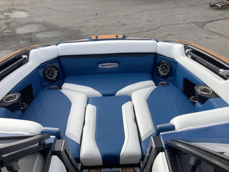 Slide: The Image of Interior of a 2023 Supra SE boat with blue and white seating. - 23