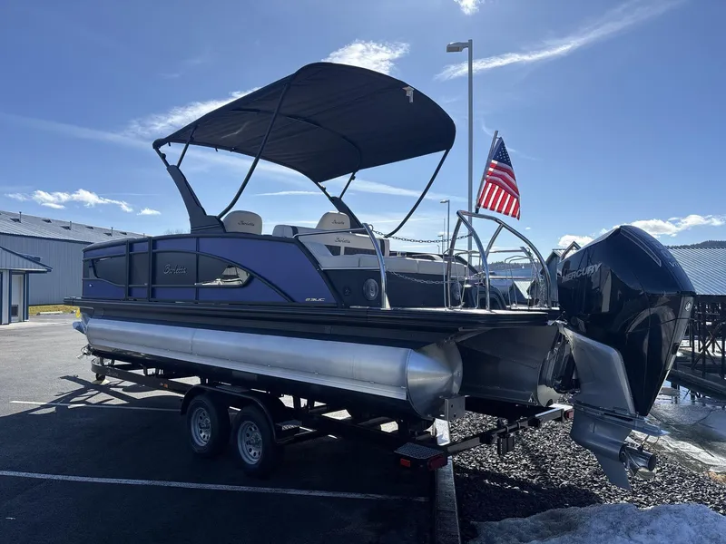 Slide: The Image of 2025 Barletta Lusso L23UC pontoon boat on trailer, American flag, sunny day. - 4