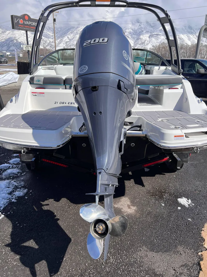 Slide: The Image of 2023 Regal 21 OBX boat with powerful outboard motor, parked on snowy pavement. - 23