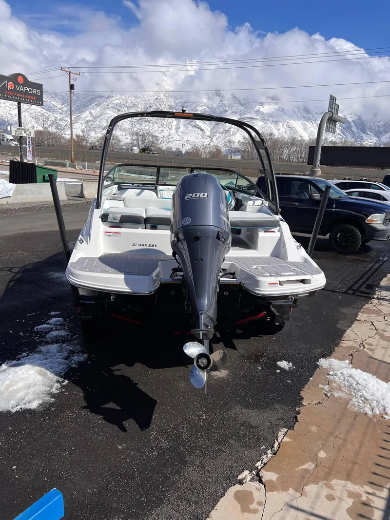 Slide: The Image of 2023 Regal 21 OBX boat with outboard motor, parked on snowy pavement. - 8