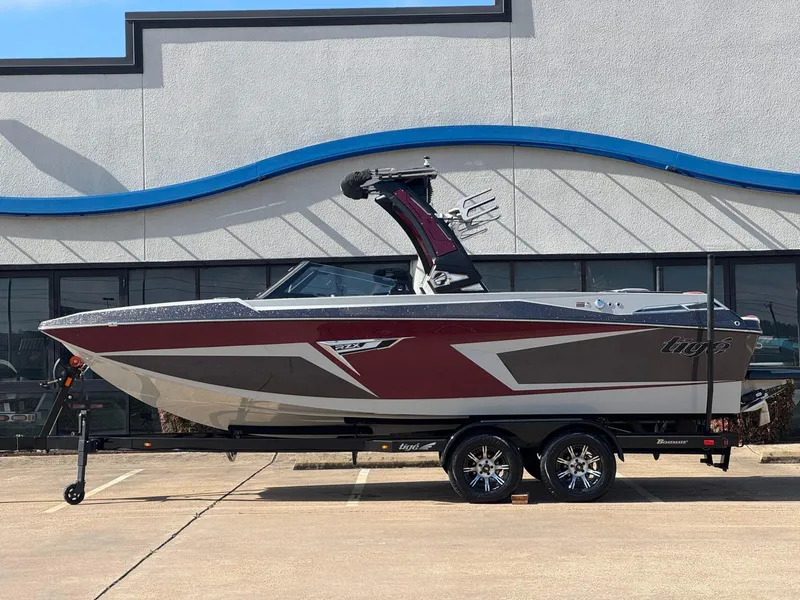 Slide: The Image of 2023 Tigé 22RZX boat on trailer, parked outside a building. - 1