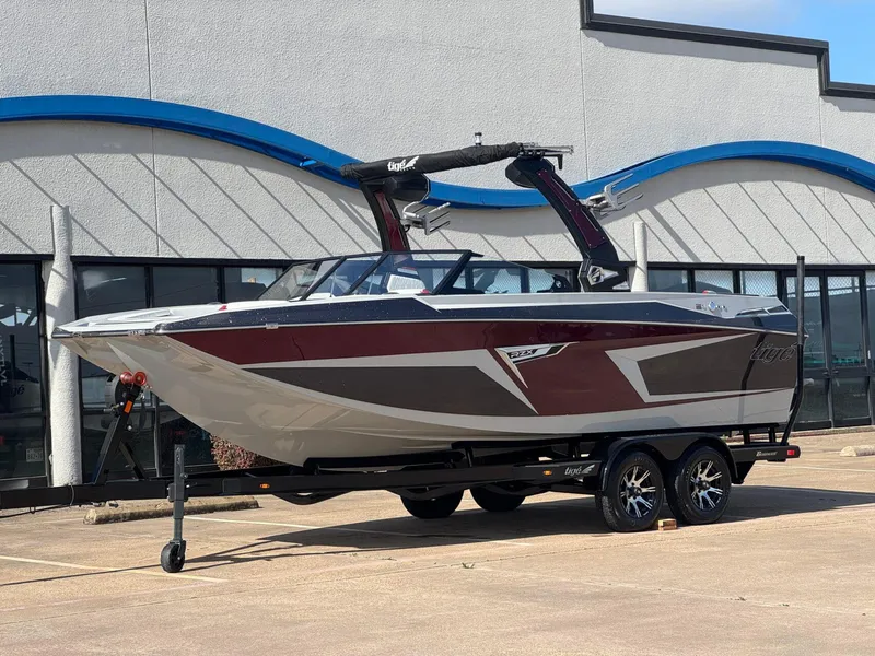 Slide: The Image of 2023 Tigé 22RZX boat on trailer, parked outside a building. - 2