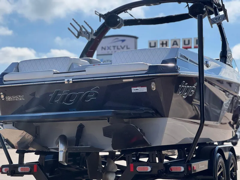 Slide: The Image of 2023 Tigé 22RZX boat on trailer, rear view, under clear sky. - 6