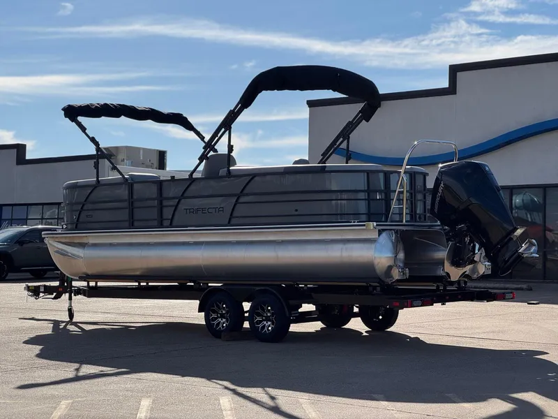 Slide: The Image of 2025 Trifecta 24RF CS 3.0 pontoon boat on trailer, parked outdoors. - 10