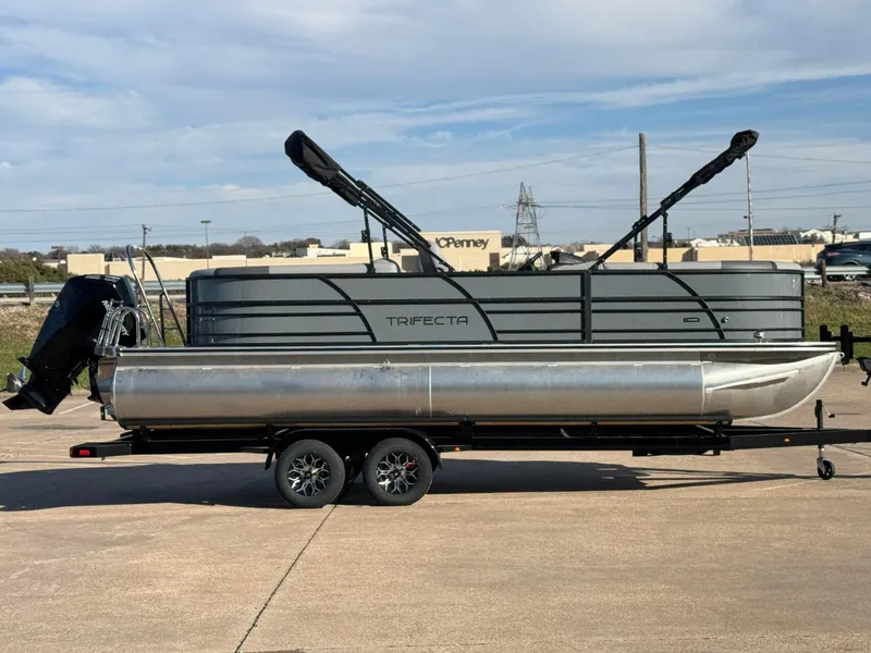 Slide: The Image of 2025 Trifecta 24RF CS 3.0 pontoon boat on trailer, parked outdoors. - 3