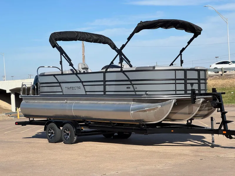 Slide: The Image of 2025 Trifecta 24RF CS 3.0 pontoon boat on trailer, parked outdoors. - 4