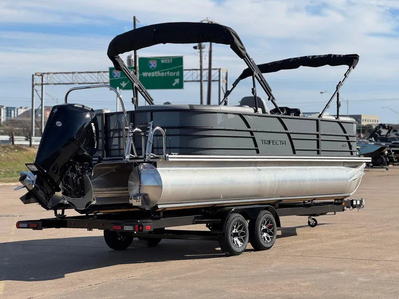Slide: The Image of 2025 Trifecta 24RF CS 3.0 pontoon boat on trailer, parked near highway signs. - 9