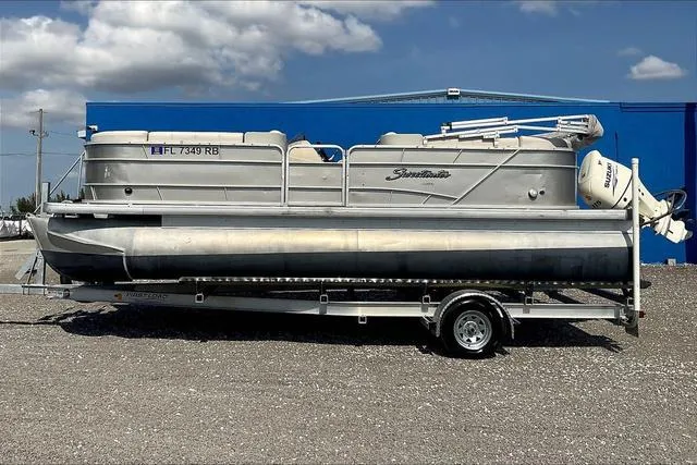 Slide: The Image of 2016 Sweetwater SW 2286 pontoon boat on trailer, parked outdoors under a blue sky. - 4